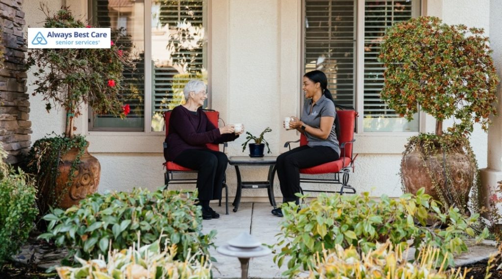  Caregiver talking with an older woman over tea on a patio.