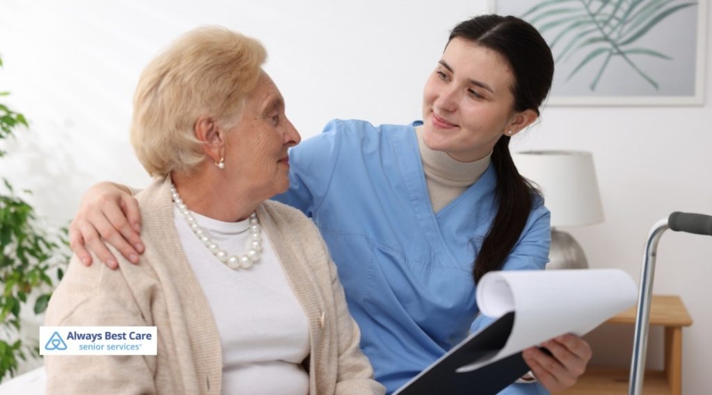 Caregiver in blue scrubs gently holds an older adult’s hands.