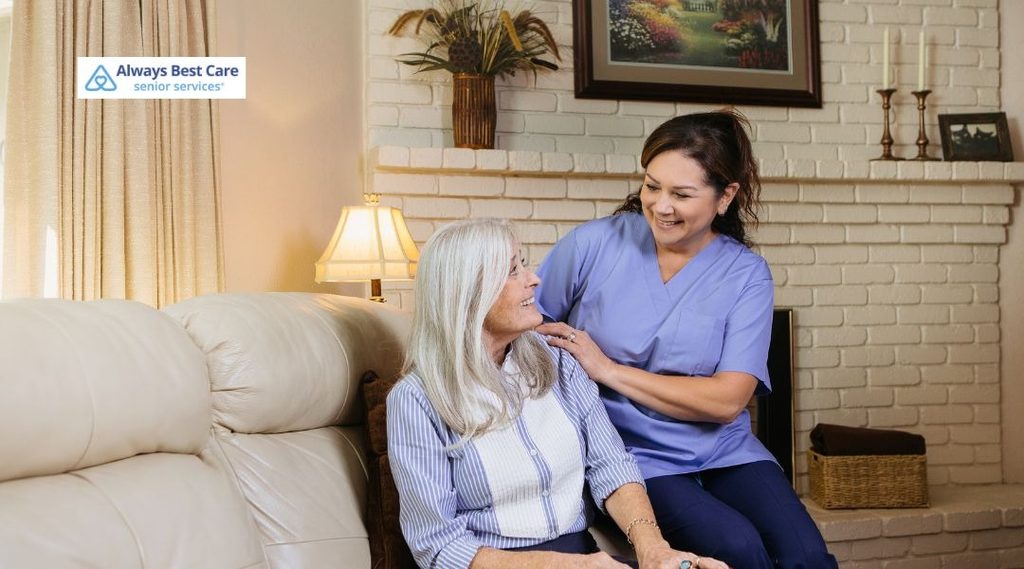 Always Best Care caregiver having a warm conversation with an older woman seated comfortably at home.