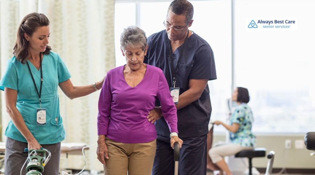 Care team helping an older woman walk safely during post-hospital recovery at home