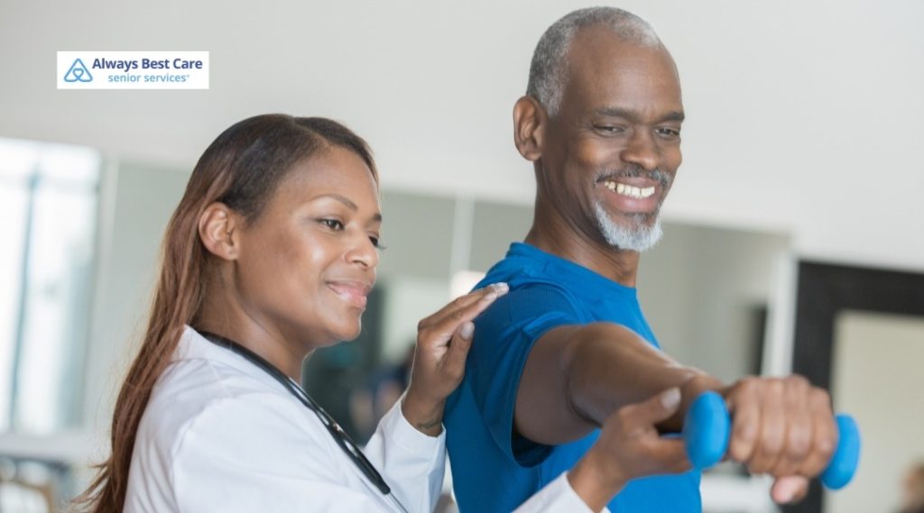 Always Best Care clinician assisting a man with arm strengthening exercises using a blue hand weight.
