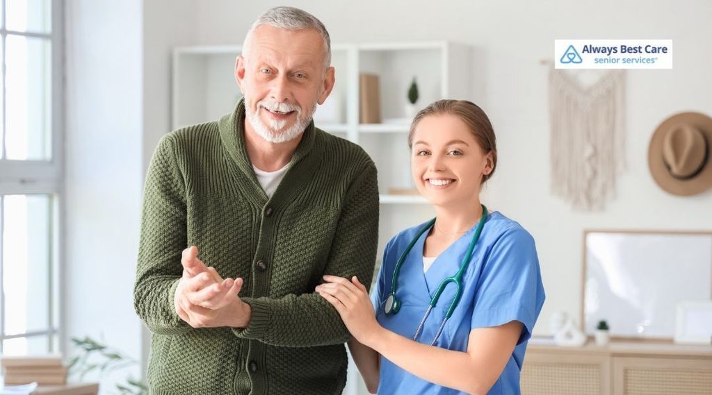Smiling nurse with a stethoscope holding the arm of an older man to help him walk at home.