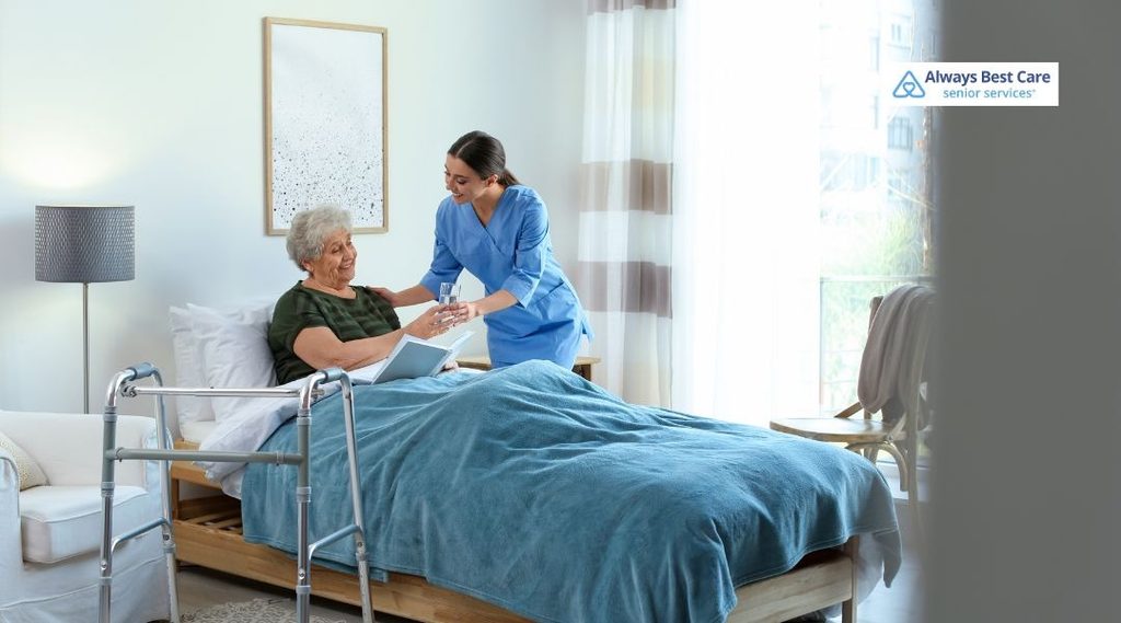 Always Best Care caregiver helping an older woman sit comfortably in bed at home.