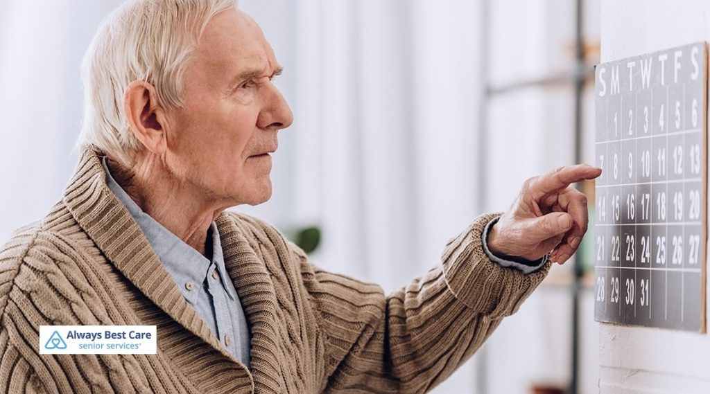 Senior man pointing to a date on a wall calendar at home.