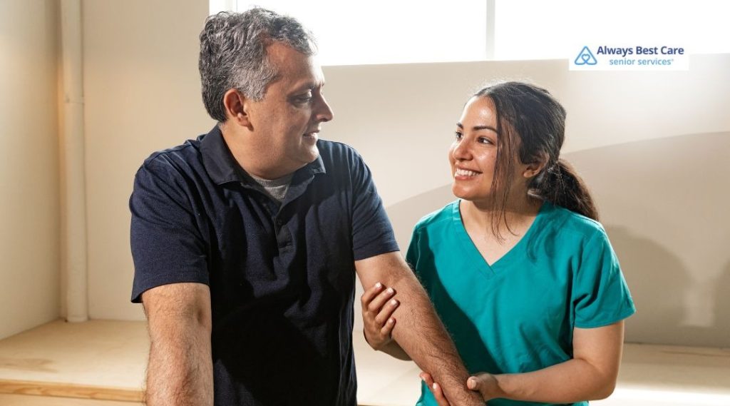 Caregiver and older couple smiling together during a supportive in-home care visit