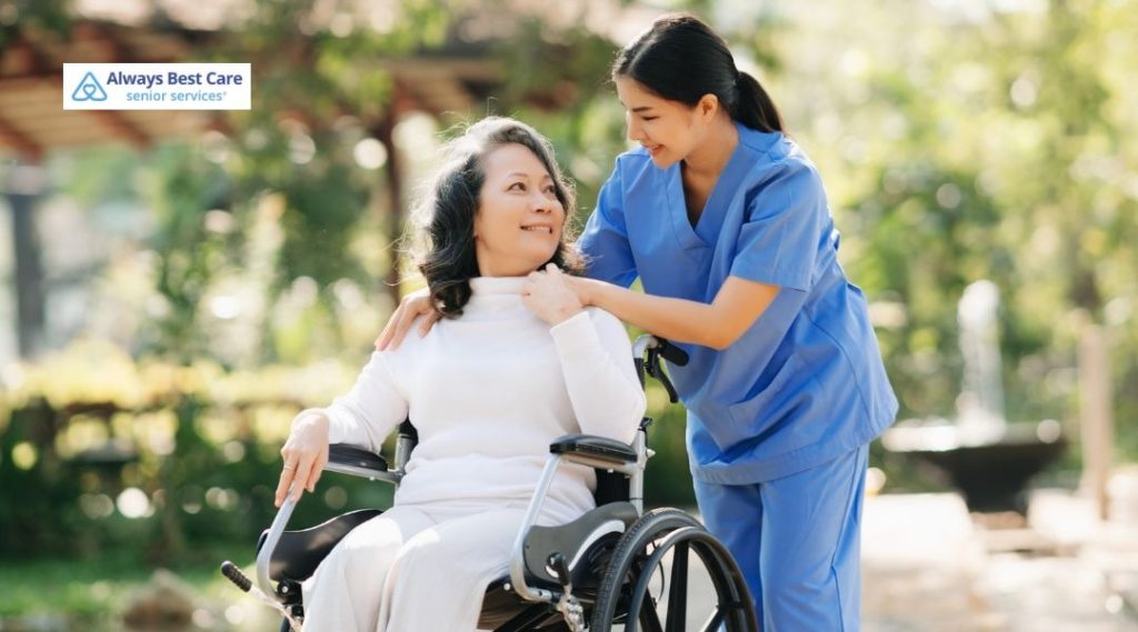 Caregiver assisting an older woman in a wheelchair outside, providing support and companionship in a sunny garden setting.