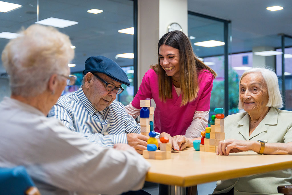 NURSE ENCOURAGING ELDER PEOPLE PLAYING SKILL GAMES IN A NURSING HOME