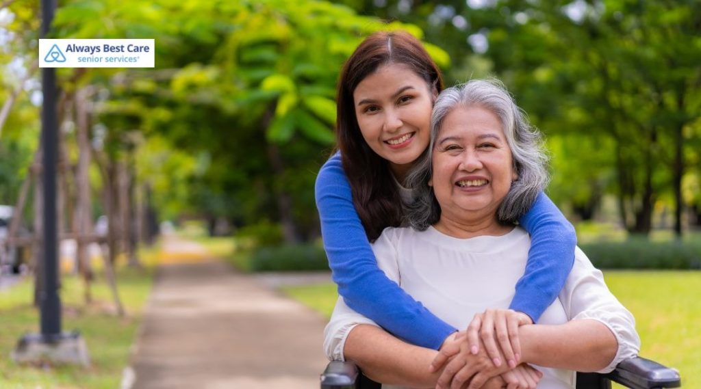 A smiling caregiver embraces an elderly woman in a wheelchair outdoors, showcasing warmth, companionship, and quality home care from Always Best Care of Worcester.