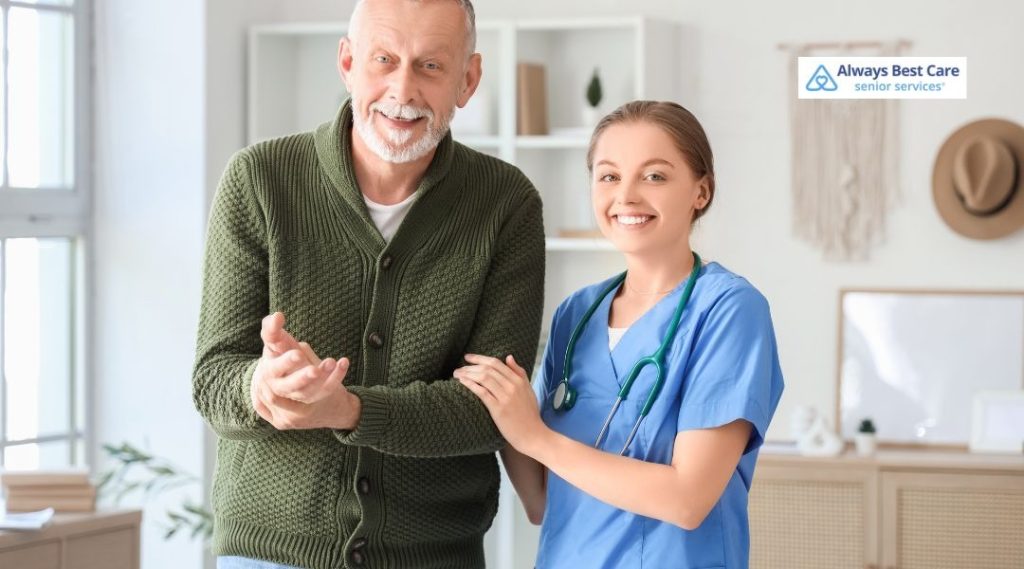 Nurse in blue scrubs standing beside an older adult and gently holding his arm, representing steady assistance and confidence with mobility.