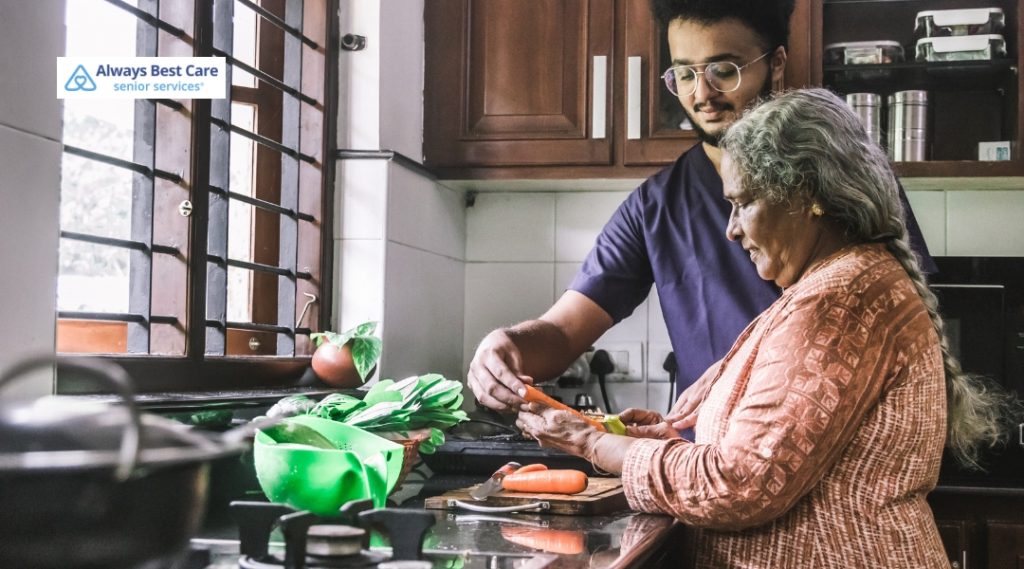 A caregiver helps an elderly woman prepare fresh vegetables in the kitchen, encouraging independence and healthy eating.