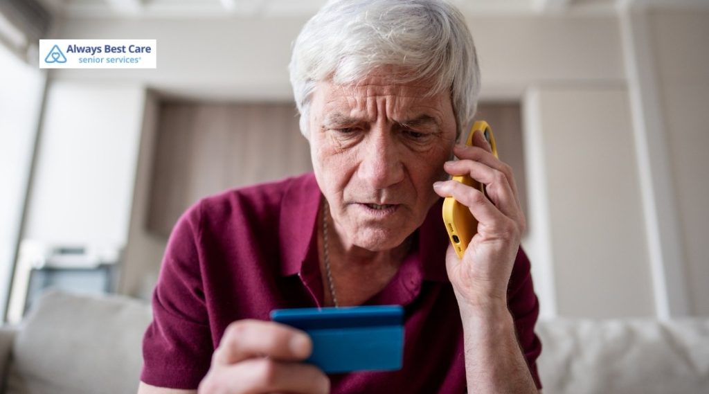 Worried older man on the phone, examining a bank card while questioning a suspicious call.