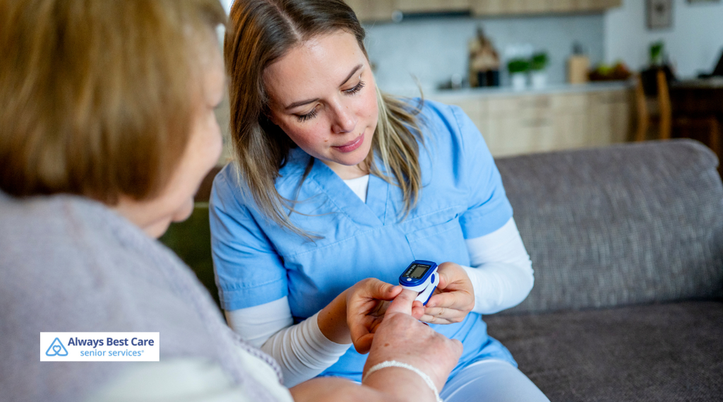 Caregiver using a lancing device to test an older woman’s blood sugar while seated at home.