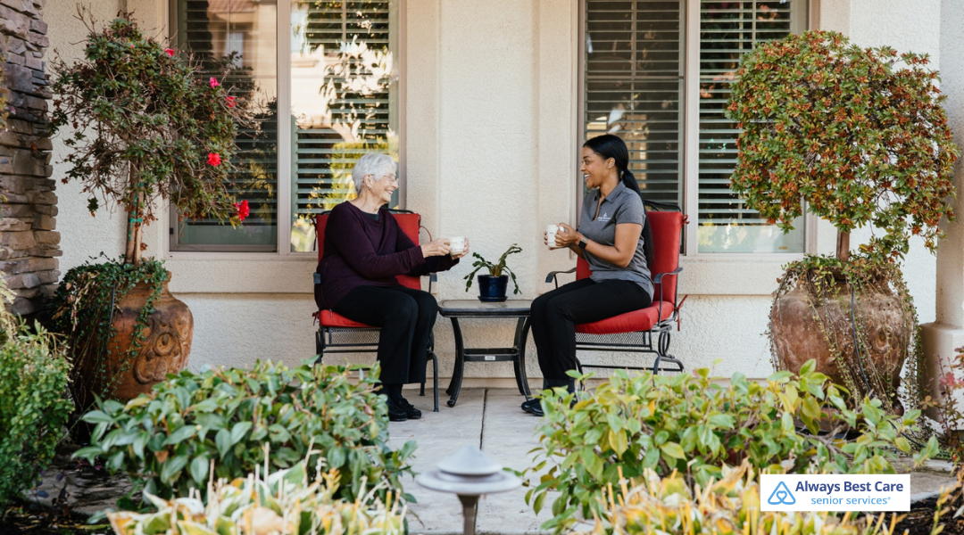6. CAREGIVER AND SENIOR WOMAN SITTING ON A PATIO, SHARING COFFEE AND CONVERSATION IN A CALM OUTDOOR SETTING.