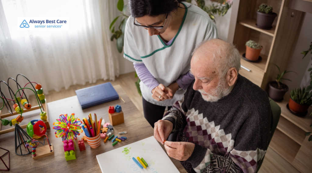 CAREGIVER ASSISTING AN OLDER MAN WITH A COLORFUL ARTS-AND-CRAFTS ACTIVITY.