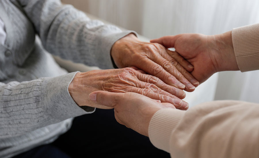A senior holding hands with her caregiver