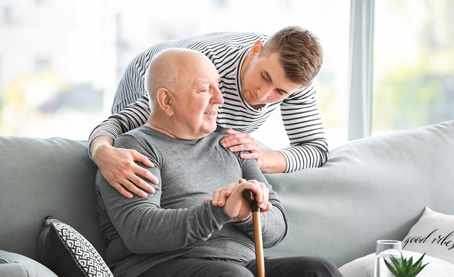 A younger male caregiver is taking care of a senior​
