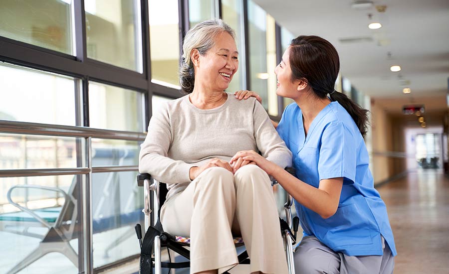 A caregiver smiling at a patient with dementia​