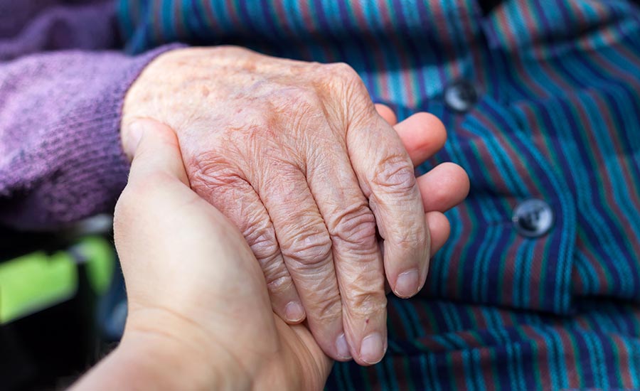 A dementia patient holding a caregiver's hand​