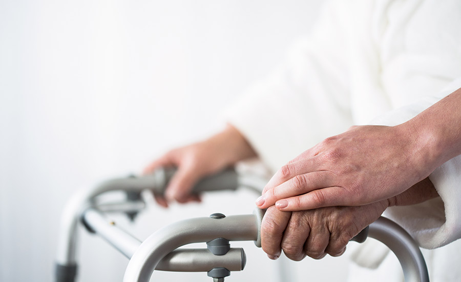 An elderly patient holding onto a walker​