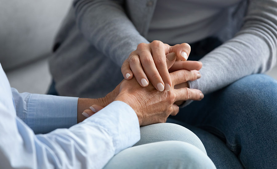 A family caregiver holding a senior female's hands​
