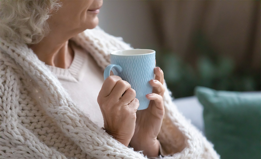 An elderly woman holding a cup of coffee​
