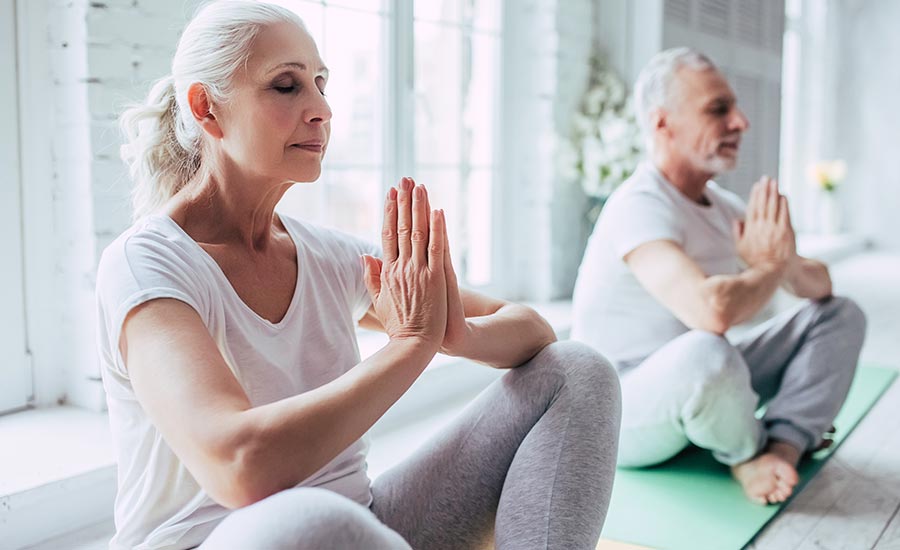 Two elderly individuals practicing yoga​
