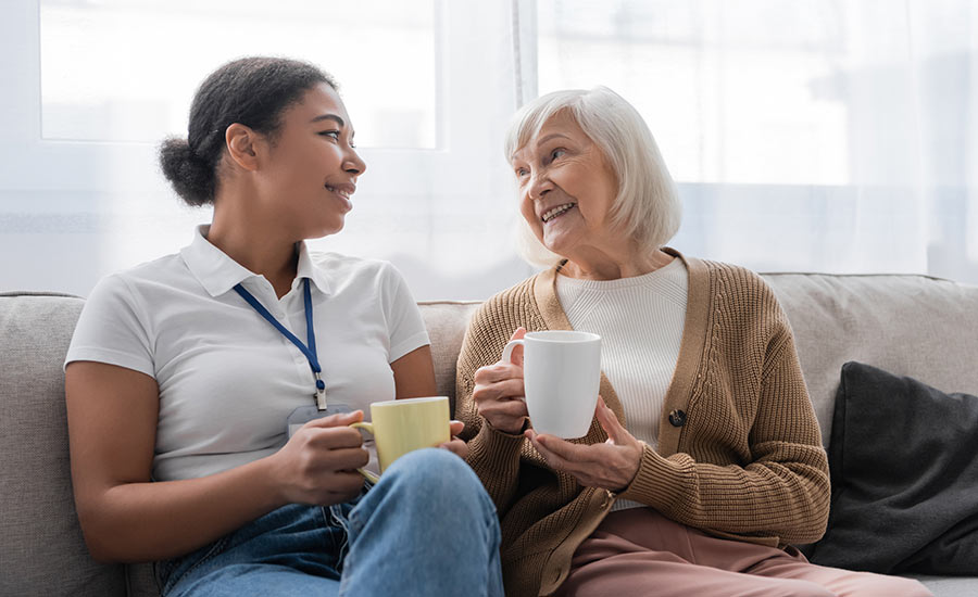 A caregiver having a cup of coffee with a senior woman​