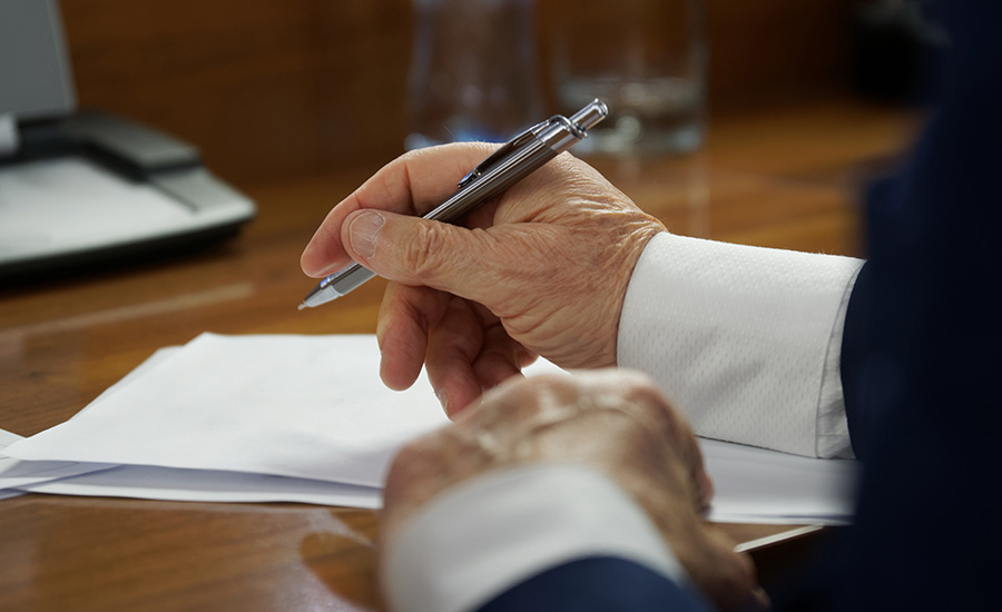 An elderly man signing documents​