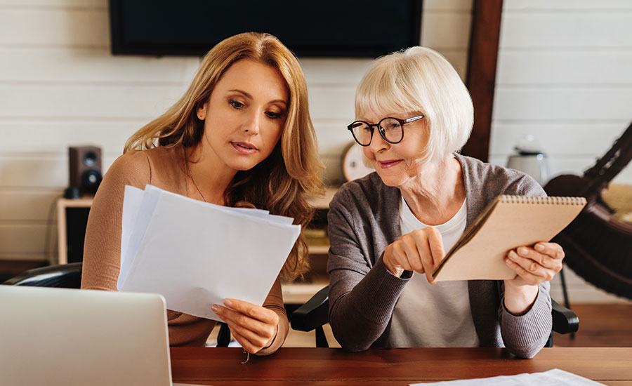 An elderly woman and her adult child looking at documents​