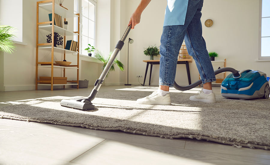 A caregiver vacuuming a carpet