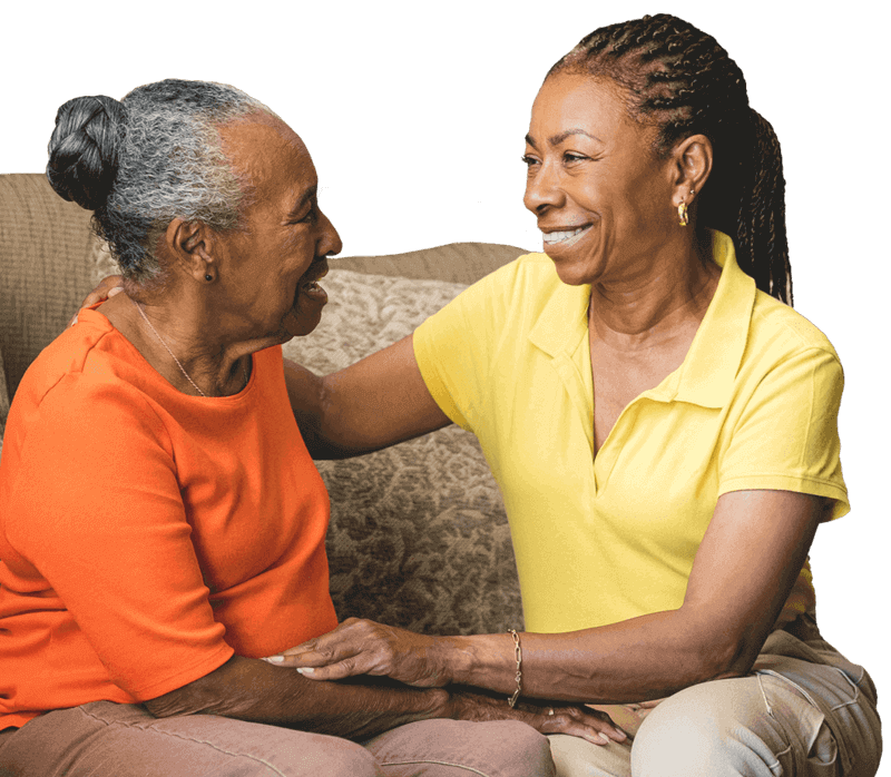 Daughter sitting with a senior on the couch, sharing a meaningful moment and emotional support at home